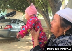 Жительница села Достык пенсионерка Гульсым Калдарбекова с внуком во дворе своего дома. Туркестанская область, 5 октября 2021 года