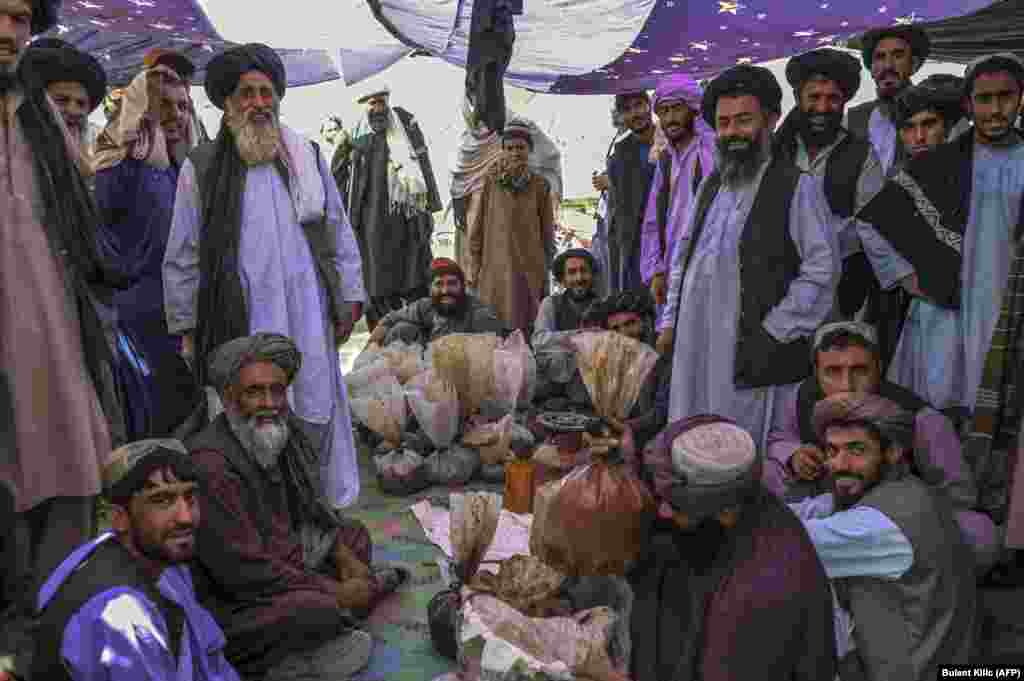 Men gather around bags of heroin and hashish as they negotiate at a drugs market on the outskirts of Kandahar on September 24.&nbsp;