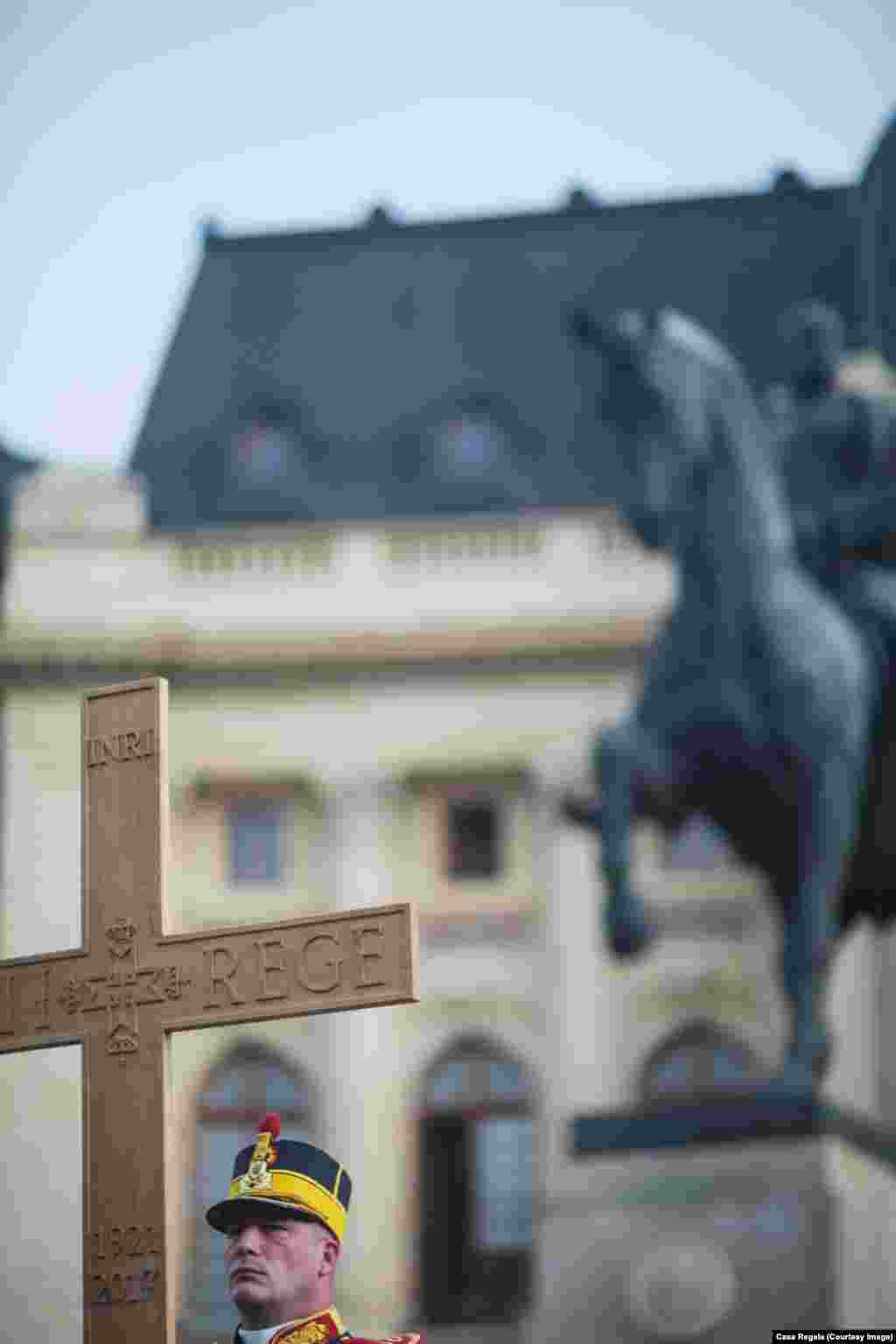 Piața Palatului, crucea Regelui Mihai I al României. Pe fundal, statuia Regelui Carol I, întemeietorul României moderne.