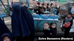 A woman shops with her children at a market in Kabul.