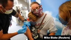 Мешканка США Моніка Стрікланд тримає на руках свого 6-річного сина Ліама, який отримує щеплення проти коронавірусу. 3 листопада, 2021. Сан Дієго, Каліфорнія