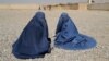Displaced Afghan women wait to receive aid from the UNHCR on the outskirts of Kabul in October.