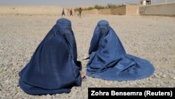 Displaced Afghan women wait to receive aid from the UNHCR on the outskirts of Kabul in October.