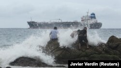 Ljudi na plaži dok tropska oluja Rik jača u uragan kod meksičke obale u Akapulku, 24. oktobar 2021.