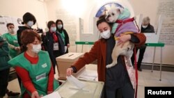 Žena drži psa dok glasa na biračkom mestu tokom drugog kruga opštinskih izbora u Tbilisiju, Gruzija, 30. oktobra 2021. 