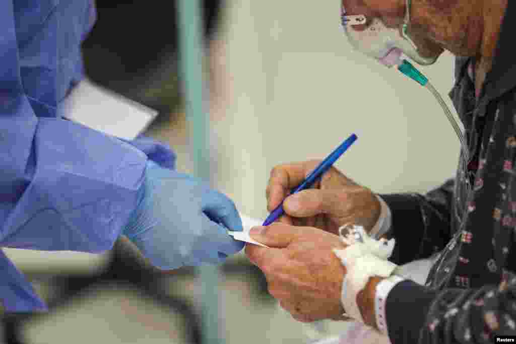 A COVID-19 patient writes down the phone number of his daughter for medical staff in the Bagdasar-Arseni Hospital.