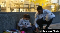 عکس سرباز راهور در حال کمک کردن به کودک دستفروش برای نوشتن تکالیفش که توسط وحید سرابی، عکاسی خبری گرفته شده است