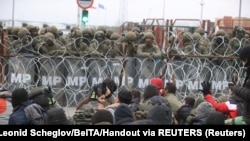 Migrants gather on the Belarusian-Polish border, while Polish military police stand guard on the Polish side of the frontier, at the Bruzgi-Kuznica border crossing on November 15.