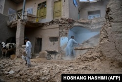 Residents clear debris from a flood-affected home following a flash flood triggered by heavy rains in the Guzara district of Herat Province on May 6.