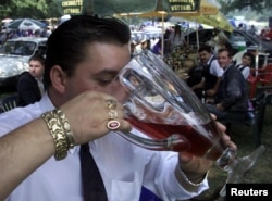 A Romany man chugs red wine from a pitcher at an open-air party in Costesti, west of Bucharest, in 2002.
