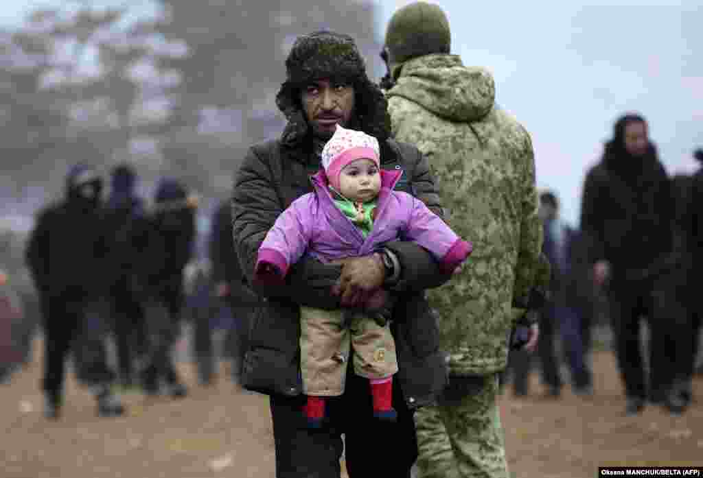 A migrant carrying a child walks in a camp near the Belarusian-Polish border in Belarus&#39;s Hrodna region&nbsp;