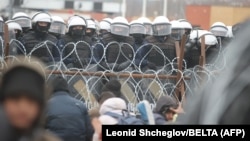 Migrantët në kufirin Bjellorusi-Poloni para një gardhi dhe një numër ushtarakësh polakë. 