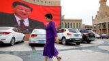 An ethnic Uyghur woman walks in front of a giant screen showing Chinese President Xi Jinping in the main square in the city of Kashgar in the Xinjiang Uyghur Autonomous Region. (file photo)