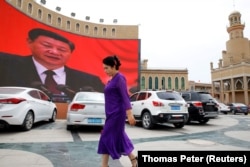 Жінка-уйгурка на площі в місті Кашгар проходить повз екран, на якому зображений китайський лідер Сі Цзіньпін