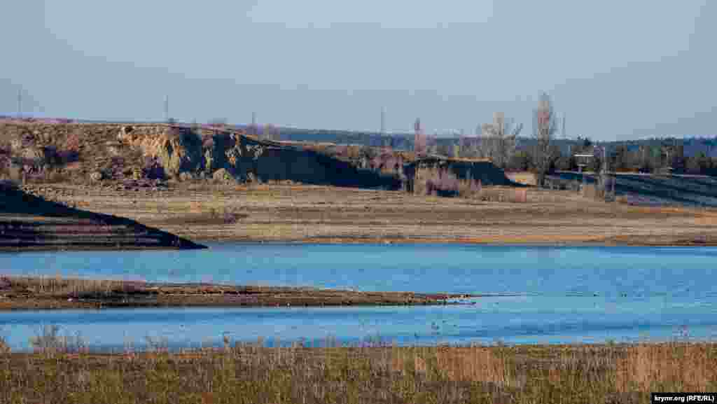 Між тополями праворуч починається 620-метрова перепускна споруда, що з&#39;єднує Білогірське водосховище з Тайганським. Деякі старожили довколишніх сіл, зокрема, Карасівки та Криничного, які добре пам&#39;ятають відкриття Білогірського водосховища на початку сімдесятих років минулого століття, по-старому називають його &laquo;новим Тайганом&raquo;, а Тайганське &ndash; &laquo;старим Тайганом&raquo;