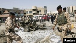 Iraqi soldiers survey the site of one of the bomb attacks in Karbala on March 29.