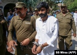 Policemen escort a handcuffed Muhammad Waseem after he leaves a court in Multan following his guilty verdict in 2019.