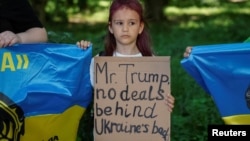 Момиче държи плакат с надпис "Г-н Тръмп, без сделки зад гърба на Украйна" на демонстрация пред посолството на САЩ в Украйна преди срещата между президента на САЩ Доналд Тръмп и руския президент Владимир Путин. Киев, Украйна, 15 август 2025 г.