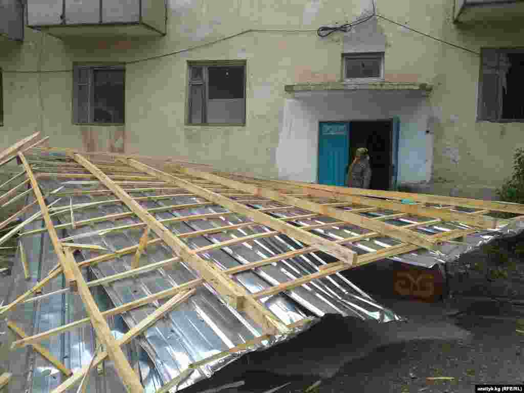 A woman inspects the damage after strong winds in Naryn, Kyrgyzstan ripped off the roof of her home. (RFE/RL&#39;s Kyrgyz Service)