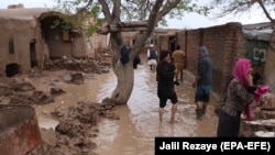 Afghan people survey their damaged houses after flooding in Herat on March 29.