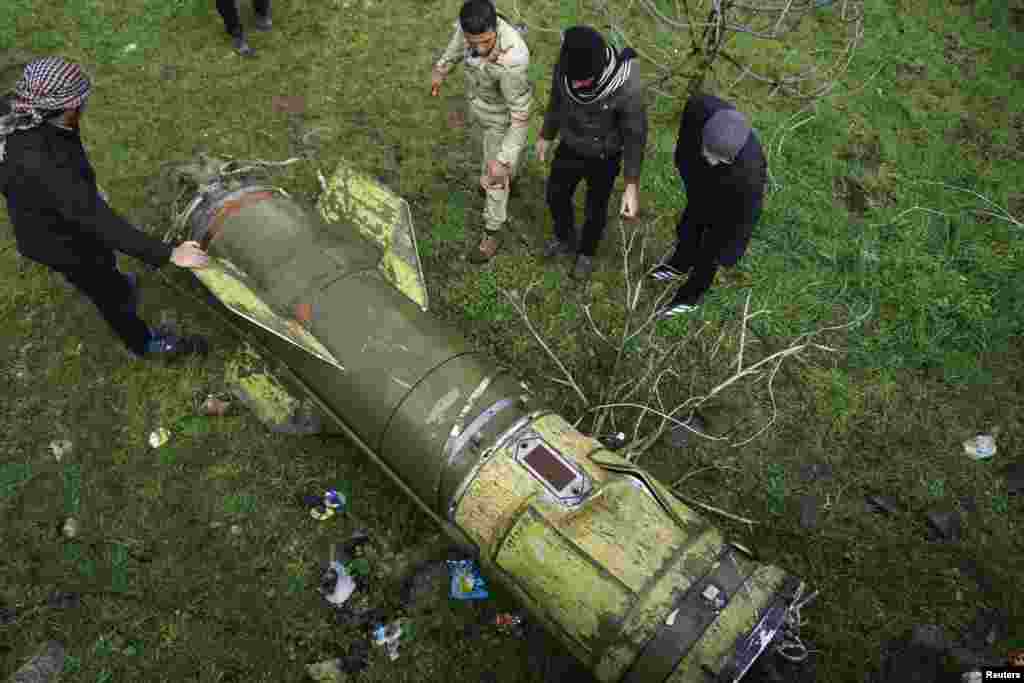 Syrian rebel fighters inspect a piece of a rocket that landed in an area that connects the northern regions of Deraa and Quneitra on February 22. (Reuters/Alaa al-Faqir)