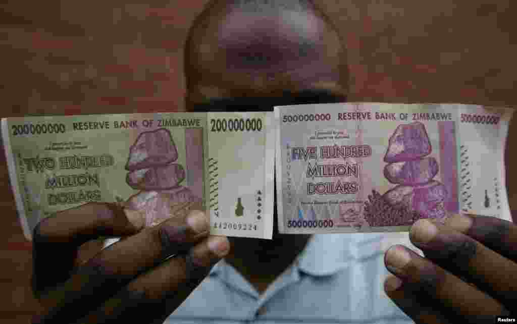 Мужчина держит в руках банкноты в 200 и 500 миллионов зимбабвийских долларов.