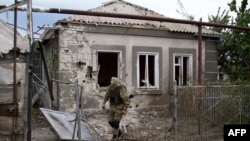 Український військовослужбовець біля зруйнованого внаслідок обстрілу будинку. Селище Сартана. 17 серпня 2015 року