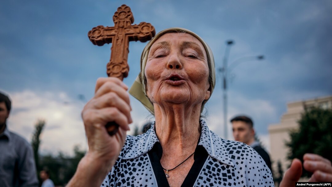 O femeie care se roagă în timpul unei manifestații în fața guvernului