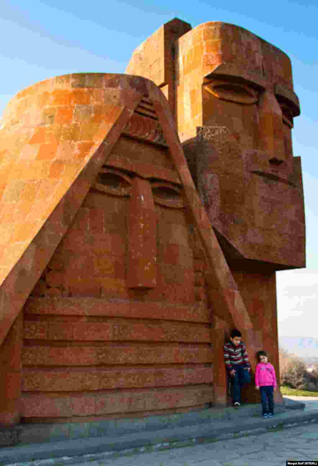 Kids pose by a monument titled &quot;We Are Our Mountains,&quot; informally known as &quot;Grandma and Grandpa.&quot; The 1967 sculpture is recognized as a symbol of Nagorno-Karabakh.