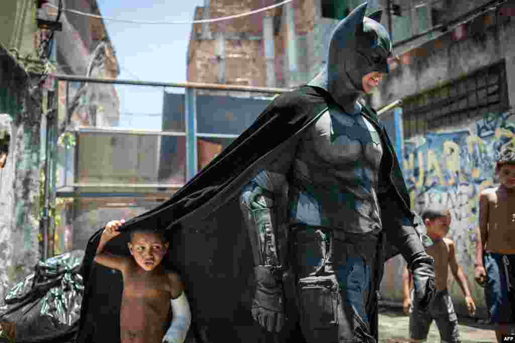 A child plays under the cape of a man in a Batman costume in the Favela do Metro slum area, near Maracana Stadium in Rio de Janeiro, where shanties are being leveled to renovate the area ahead of the Brazil&#39;s hosting of the FIFA World Cup in June. (AFP/Yasuyoshi Chiba)