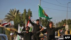 Members of the Hashed Shaabi (Popular Mobilisation) paramilitary forces flash the victory gesture as they wave flags of the organisation and its groups while parading in the streets of the central holy shrine city of Karbala on December 10, 2018, as they 