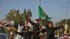 Members of the Hashed Shaabi (Popular Mobilisation) paramilitary forces flash the victory gesture as they wave flags of the organisation and its groups while parading in the streets of the central holy shrine city of Karbala on December 10, 2018, as they 