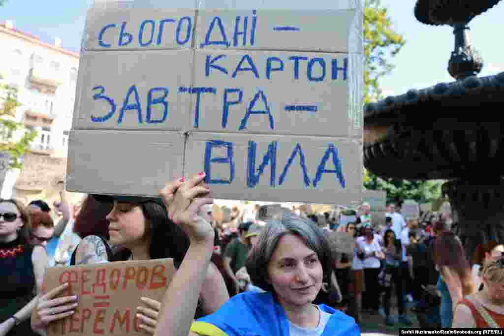 Жінка тримає картонку з написом: «Сьогодні картон, завтра – вила»