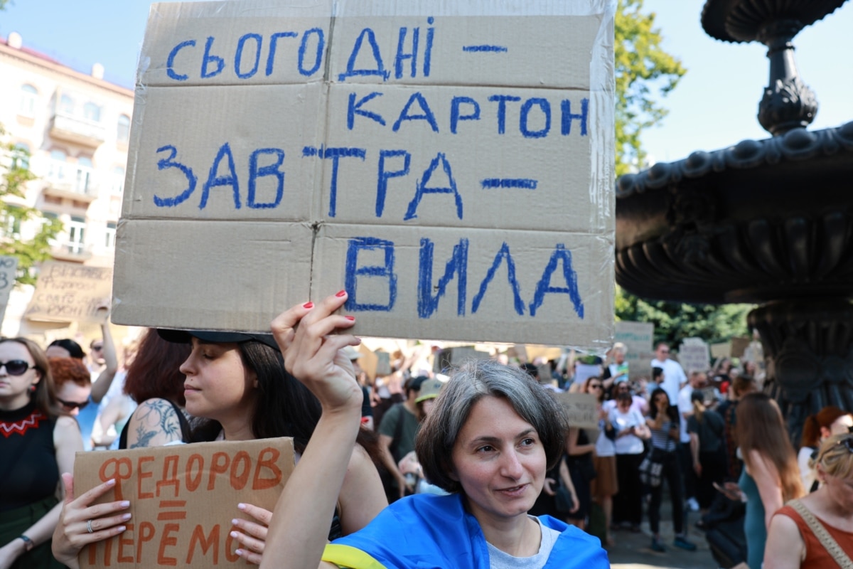 Жінка тримає картонку з написом: «Сьогодні картон, завтра – вила»