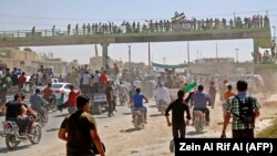 Syrians chant slogans and wave flags of the opposition as they protest against a promised government assault on Idlib province.