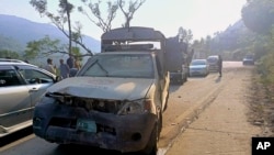 Vehicles drive past a damaged police vehicle that was escorting a convoy of foreign diplomats near Malam Jabba in Pakistan's Khyber Pakhtunkhwa Province on September 22.