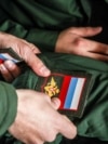 Conscripts apply arm patches to military uniform at an enlistment office in the Siberian city of Kemerovo during a military draft campaign in October 2021.