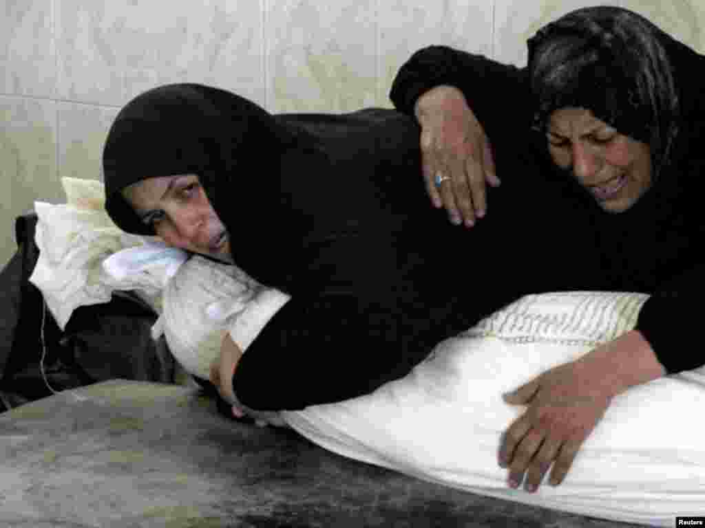 Two women mourn over the shrouded body of a victim of bomb attacks before his burial at a cemetery in Najaf, south of Baghdad, on August 26. Suicide bombers and other attackers killed at least 62 people in coordinated attacks on Iraqi security forces throughout the country on August 25, less than a week before U.S. troops formally end combat operations. Photo by Ali Abu Shish for Reuters