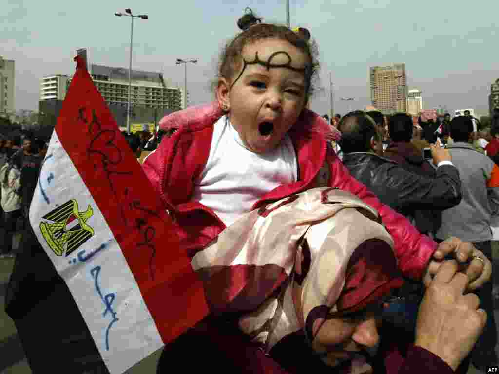 A mother carries her daughter on her shoulders with the word "Masr" or "Egypt" written on her forehead as Egyptians gather in Cairo's Tahrir Square, heeding a call by the opposition for a "march of a million" to mark a week of protests calling for the ouster of Mubarak's regime on February 1. Photo by Mohammed Abed for AFP