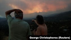 Dvoje građana Larnake posmatraju požar koji bukti na obroncima planine Troodos na jugu Kipra, 3. jula 2021. 