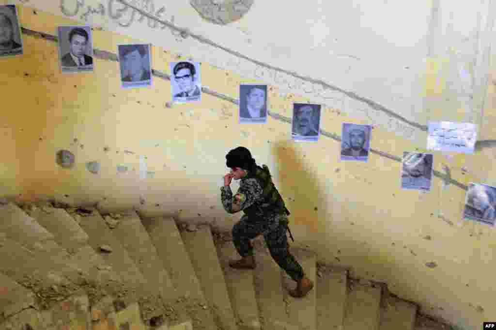 An Afghan soldier walks past photographs of victims of war on display to mark Human Rights day at the ruined Darlaman Palace in Kabul on December 10. (AFP/Aref Karimi)