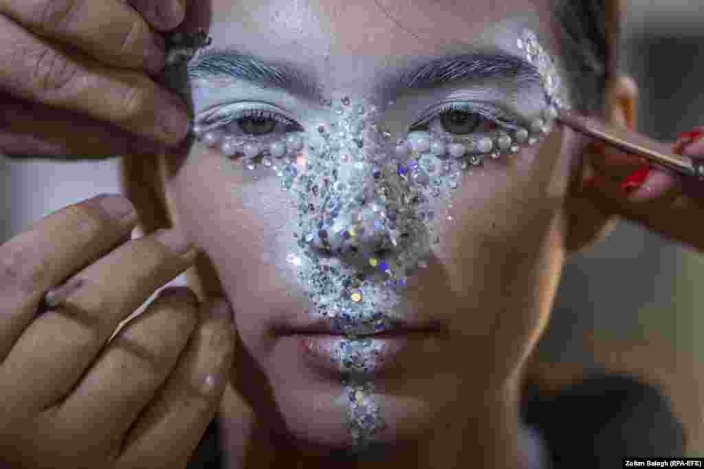 A model has her makeup done backstage prior to a show at the Budapest Central European Fashion Week at the Museum of Fine Arts in Budapest.