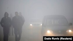 Ljudi hodaju kroz gusti smog u Kaknju, gradu u Bosni i Hercegovini
