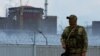  A soldier wearing a Russian flag on his uniform stands guard near the Zaporizhzhya nuclear power plant.