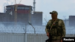  A soldier wearing a Russian flag on his uniform stands guard near the Zaporizhzhya nuclear power plant.