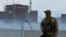  A soldier wearing a Russian flag on his uniform stands guard near the Zaporizhzhya nuclear power plant.