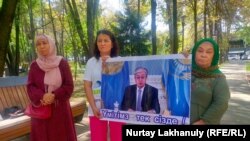 Родственники узников синьцзянских «лагерей» держат плакат с обращением к президенту Казахстана. Алматы, 5 сентября 2022 года