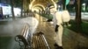 Рабочий в защитном костюме обрабатывает скамейку на улице в Худжанде. 28 апреля 2020 года. 