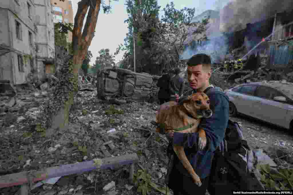 A man carries his dog through the rubble at the site of a strike in Kyiv.The Kremlin framed the attack as targeting "defense industry plants" in cities across Ukraine, in response to unspecified "terrorist acts" by Kyiv.
