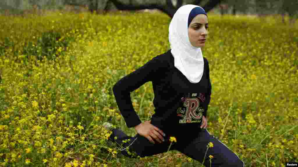 Runner Worood Maslaha stretches in a field belonging to her family in the West Bank village of Asira Ash-Shamaliya near Nablus. Four Palestinians will participate in the London Olympics. (REUTERS/Ammar Awad)